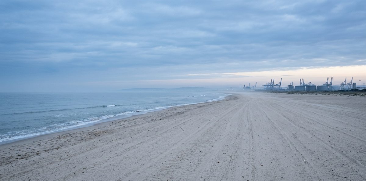 La plage du Front de Mer de Port-la-Nouvelle au petit matin, avec les grues du port de commerce à l'horizon
